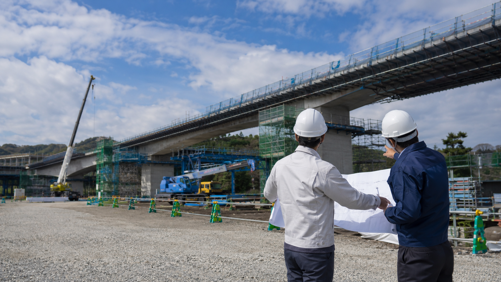 橋梁工事現場で図面を確認する作業員2名